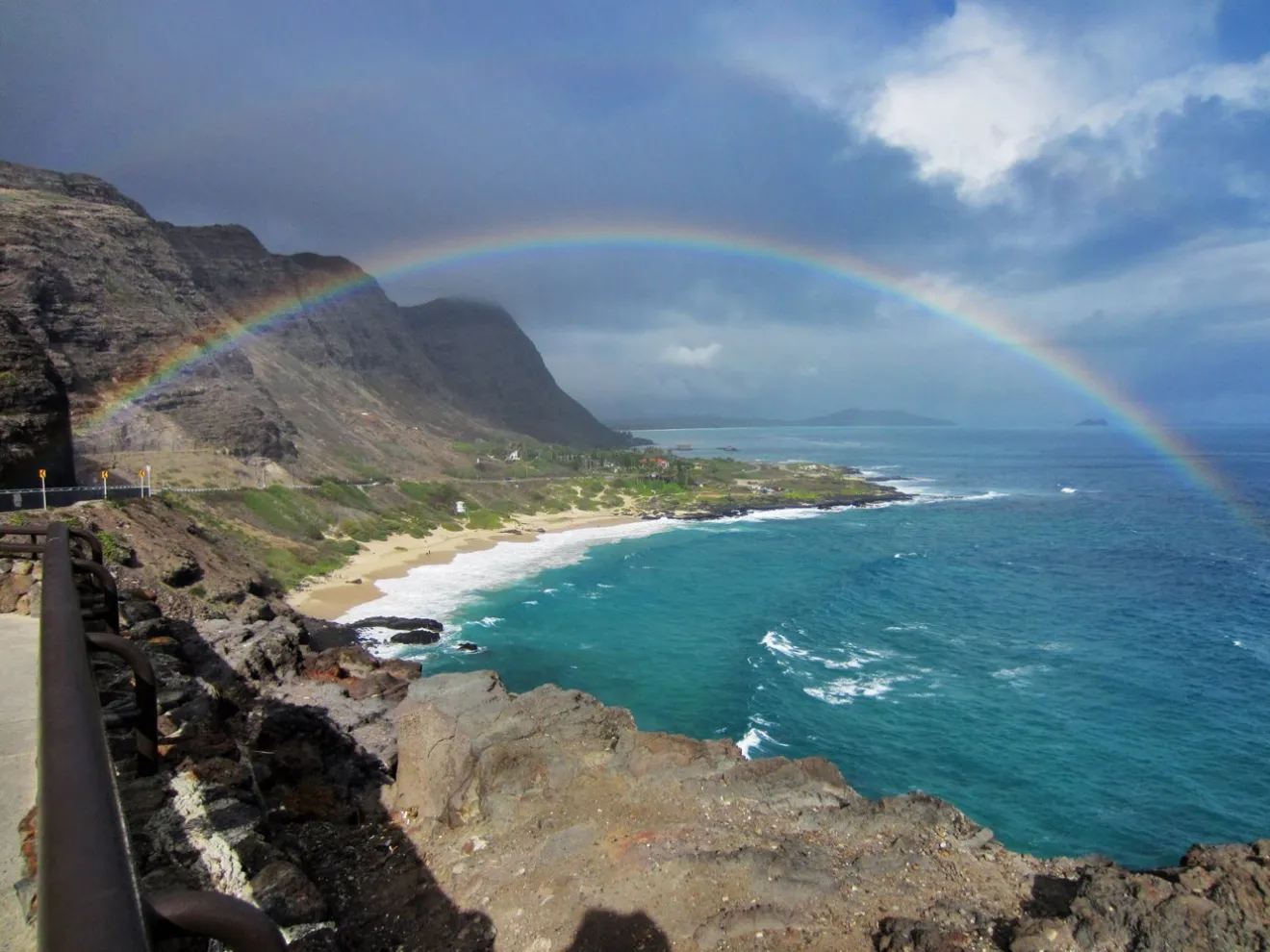 a rainbow over a body of water with a mountain in the background
